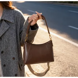 Vue détaillée du sac bandoulière en cuir marron avec large sangle tissée au coucher du soleil