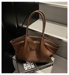 Detailed view of the dark brown lychee leather texture and metal buckle on the tote bag