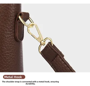Macro detail of golden metal hook on dark brown lychee leather tote bag strap