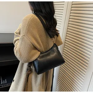 Détail du sac sous le bras en cuir souple noir avec texture brillante et crochet en métal