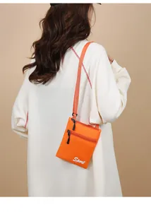 Vue détaillée d'un sac bandoulière orange en nylon avec texte Sport et fermetures éclair