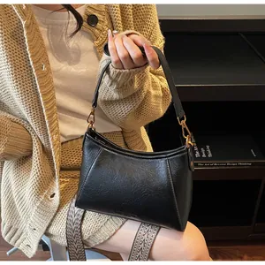 Détail du sac à main en similicuir noir avec boucles dorées et bandoulière tissée large