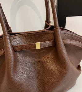 Detailed macro view of dark brown lychee textured leather tote with gold buckle
