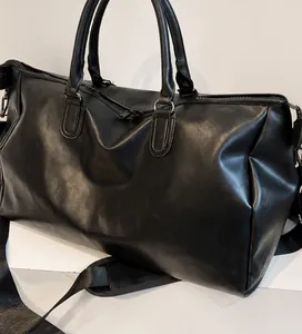 Makroansicht der schwarzen PU-Leder Reisetasche mit Doppelgriffen und Tragegurt