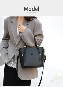 Detail of black lychee grain leather tote bag with gold hardware and shoulder strap