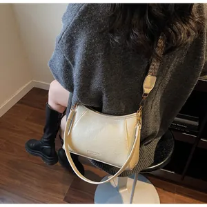 Détails du sac bandoulière beige en cuir plissé avec sangle florale sur modèle