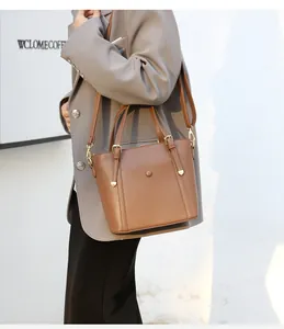 Brown lychee leather tote bag with gold hardware and adjustable strap shown on model
