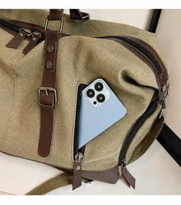 Detalle del bolsillo frontal con cremallera para móvil en una bolsa de viaje de lona verde
