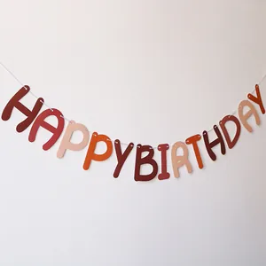 Detail of earthy tone felt Happy Birthday banner letters on a white background