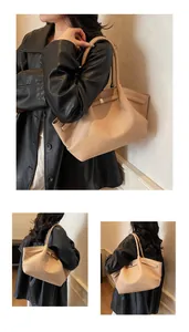 Detailed macro view of the beige lychee pattern leather and gold metal buckle on tote bag