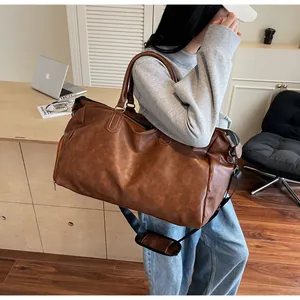 Detailansicht der braunen PU-Reisetasche mit verstellbarem Gurt und strukturierter Oberfläche