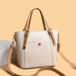 Elegant cream white bucket tote bag in pebbled leather with brown handles and gold hardware