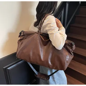 Detail einer braunen PU-Leder Reisetasche mit Doppelgriffen und Schultergurt auf Treppen