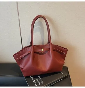 Close-up of brown lychee grain leather tote bag featuring elegant gold hardware details