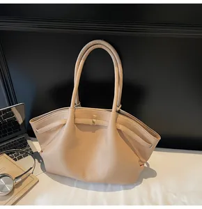 Detail of beige lychee pattern leather tote bag with gold buckle on a work desk