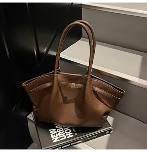Detail of dark brown lychee leather tote bag with metal buckle and shoulder strap