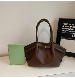 Macro detail of dark brown litchi grain leather tote bag with elegant gold buckle