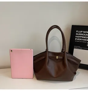 Brown lychee leather tote bag shown next to a tablet for size reference and scale