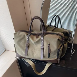 Olive green canvas travel duffel bag with leather handles and adjustable shoulder strap