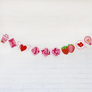 Guirlande Little Fairy rose avec motifs fraises et cœurs sur mur de briques blanches