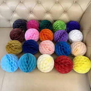 Overhead view of twenty colorful paper honeycomb balls displayed on a beige leather sofa