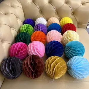 Close-up of twenty assorted colorful paper honeycomb balls arranged on a leather sofa