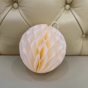 Close-up of cream honeycomb paper ball decor with detailed fold texture and white hanging cord