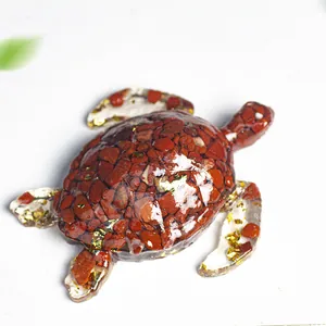 Détail d'une tortue en résine avec des pierres de cristal rouge et feuille d'or