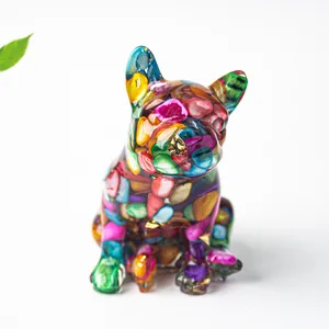 Dettaglio macro di statuetta bulldog in resina con cristalli colorati e foglia oro