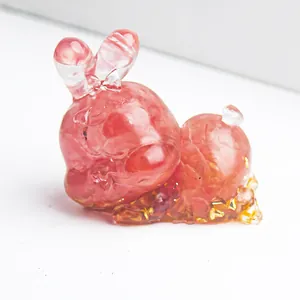 Detailed close-up of pink crystal resin rabbit statue with golden foil flakes inside