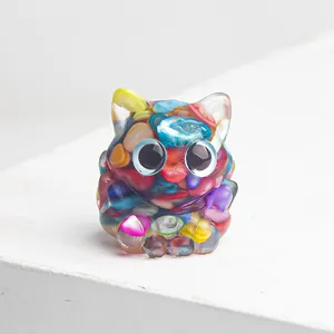 Détail d'une figurine de chat en résine colorée avec des fragments de pierres cristallines