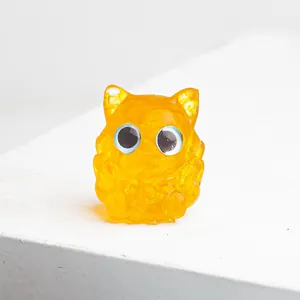 Détail d'une figurine de chouette en résine orange avec texture cristal et yeux bleus