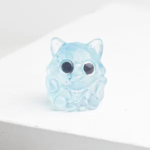 Vue macro d'une figurine de chat en résine bleu clair translucide avec collier à cloche