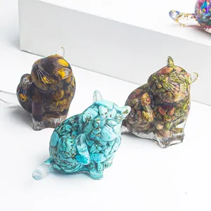 Tre statuine di gatti in resina e cristallo in vari colori su supporti bianchi