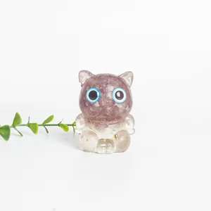 Détail d'une figurine de chat en résine rose et cristal avec de grands yeux bleus
