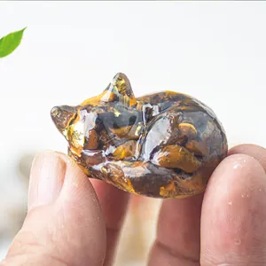 Macro detail of a resin sleeping cat figurine with Tiger's Eye stones and gold leaf foil