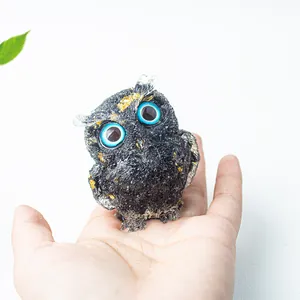 Natural crystal owl figurine with blue eyes and gold foil accents held in hand