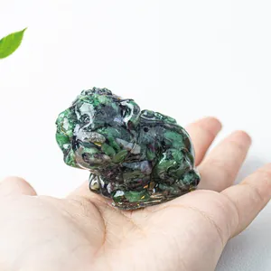 Detail of tiger resin figurine filled with natural green and purple crystals held in hand