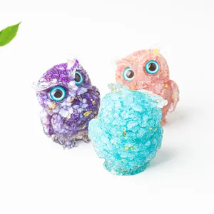 Detailed close-up of colorful crystal owl statues with gold foil flakes and blue eyes