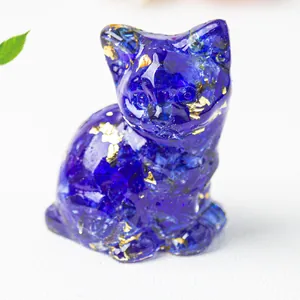 Detail of dark blue resin cat figurine with shimmering gold foil accents on white surface