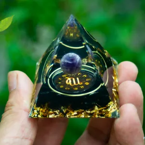 Macro shot of Orgone pyramid with amethyst ball and Virgo constellation golden emblem