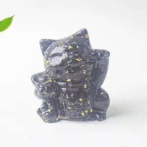 Close-up of black resin lucky cat statue with gold foil accents and a gold coin