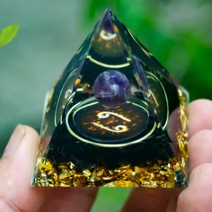 Macro shot of Cancer zodiac orgone pyramid with amethyst sphere and obsidian chips