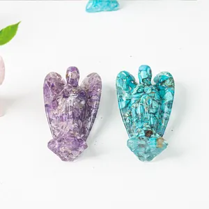 Close-up of resin angel statues with purple amethyst and turquoise crystal stones