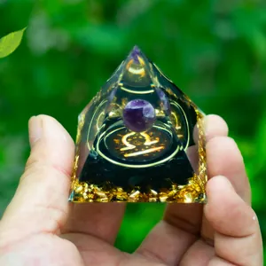 Libra crystal orgone pyramid with amethyst and gold foil in a hand for scale