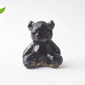 Vista dettagliata di una statuetta di orso in resina nera con texture di cristallo naturale