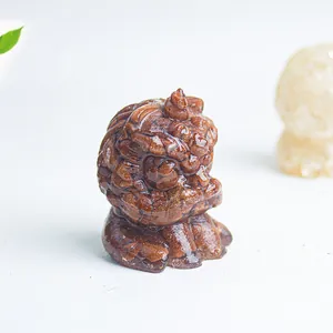 Macro shot of owl guardian figurine with brown goldstone texture on white surface