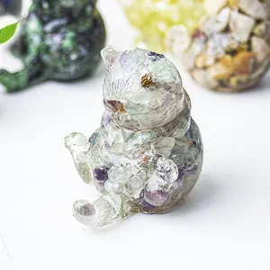 Macro di una statuetta di gatto in resina con cristalli naturali verdi e viola