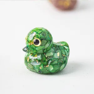 Detail van de eendenfiguur met groene kristalstenen en goudfolie harsversiering