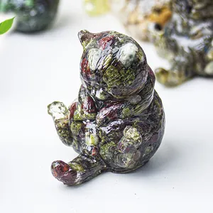 Dettaglio macro di una statuetta di gatto con pietre di cristallo naturali verdi e rosse